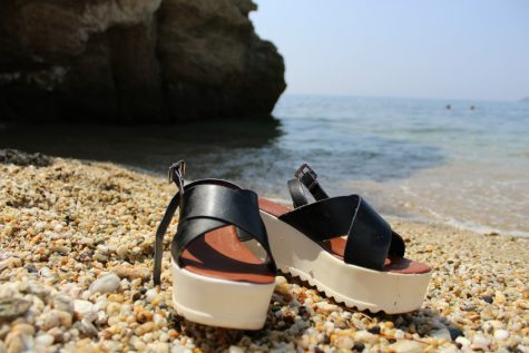 Strangie's shoes on the pebbled beach with only a book to read for entertainment.