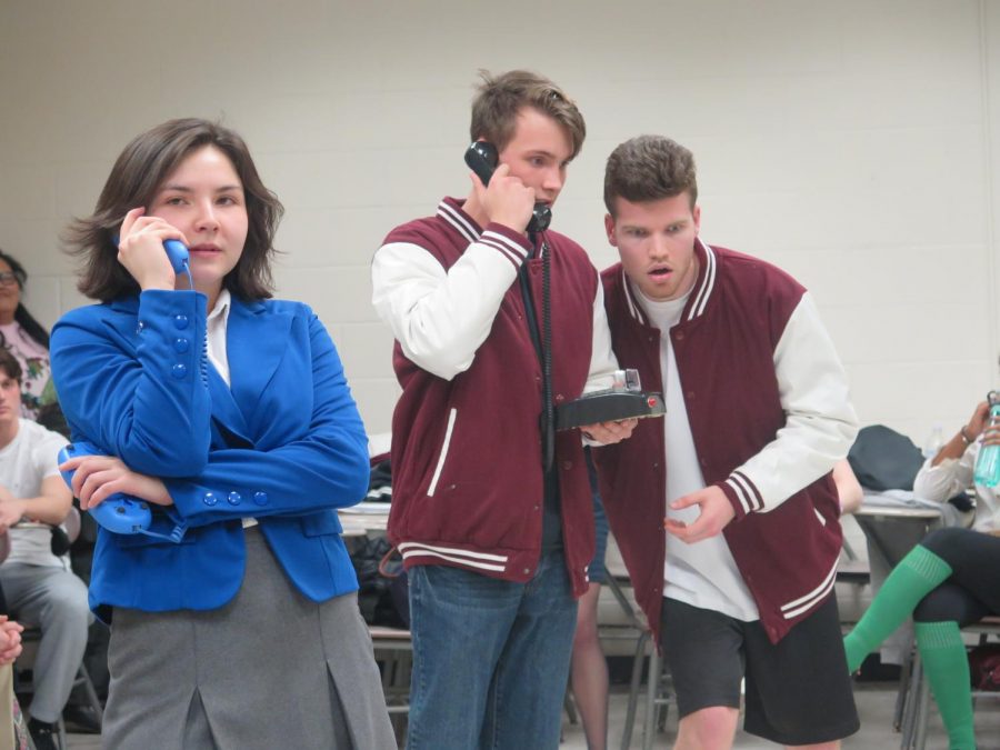 Tanya Avendaño Stockler, playing Veronica, Aidan Gerard, playing Kurt Kelly, and Henry Power, playing Ram Sweeney, act out a phone call. 
