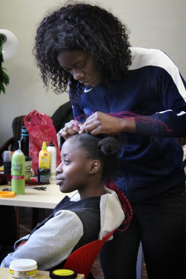 Braider Yemisi Genebar, right, works on her model, Raquel Kiddu, left, on March 23, 2018 in the Malcolm X Cultural Center located in the University of Massachusetts Amherst in Amherst, Mass. Genebar ultimately opts for a combination of techniques including free-styling. 