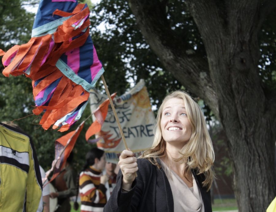 A woman gazes at a flag she is holding while participating in the XTCA Art Parade. 
(Brian Choquet/ Amherst Wire)