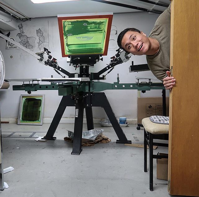 Alex Pham, owner of Alexs Printing Press, and the press machine behind him 
