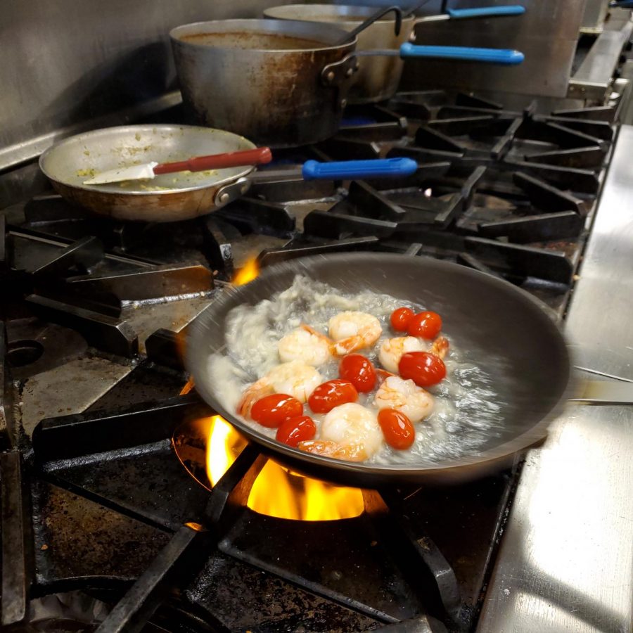 Shrimp and tomatoes sizzle away in a flaming pan 