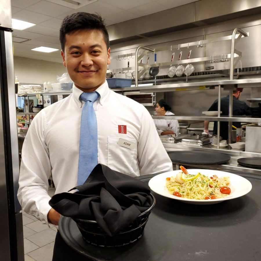 Senior Adam Shi stops for a photo before serving a meal in the dining room.
