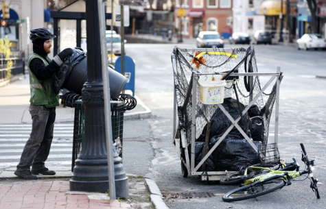 Ethan Tupelo, a member of the Pedal People, empties a trash can in downtown Northampton in April 2020. 